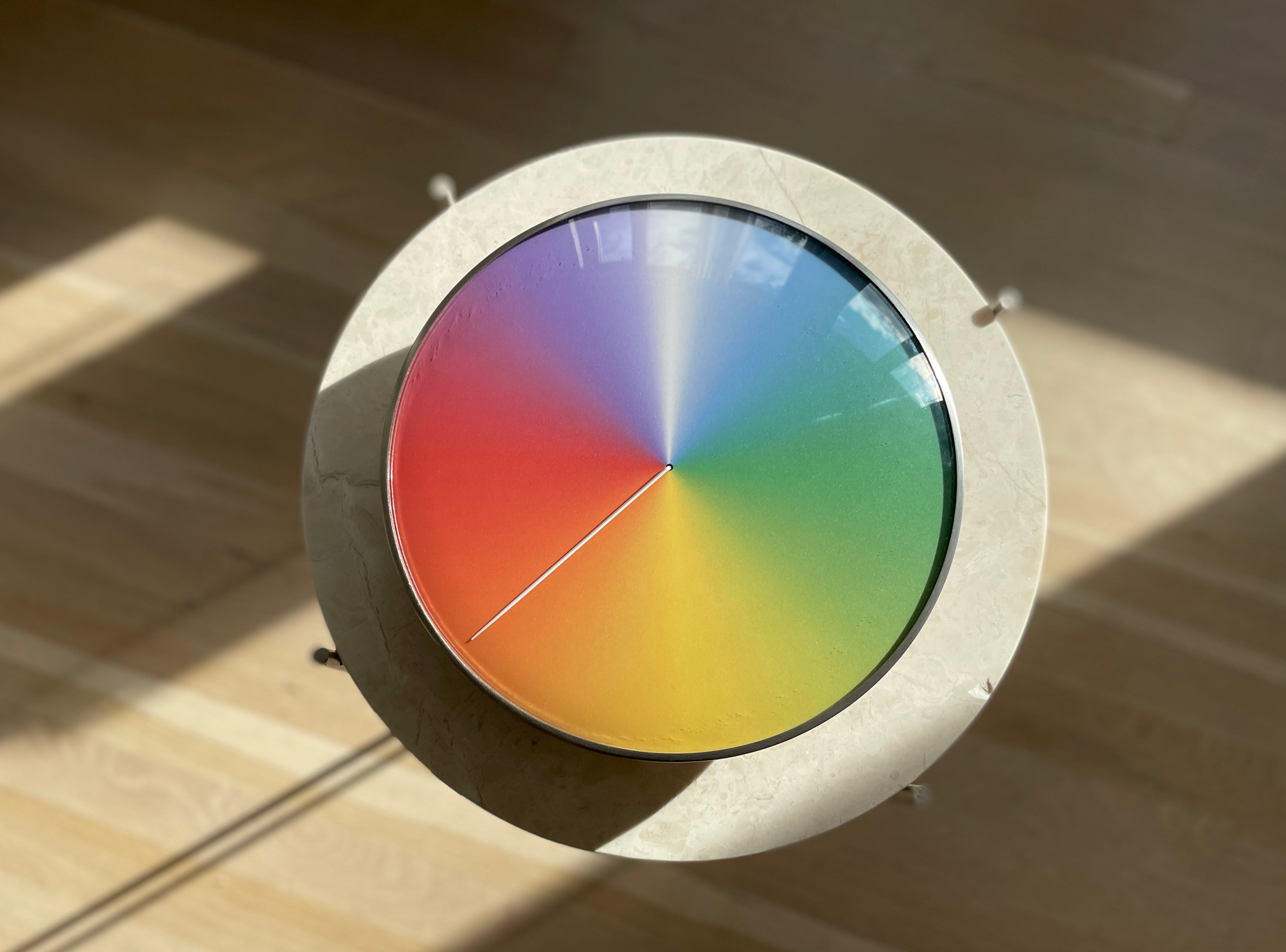 The Present - Year (steel + glass) sitting on a circular marble table in August.